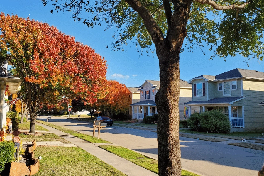 Cute and quiet neighborhood street in the fall with colorful leaves on the trees and sidewalks
